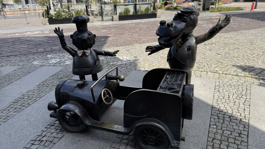 Rzeźba bohaterów bajki Porwanie Baltazara Gąbki przy zabytkowym automobilu na ulicy Bielska-Białej