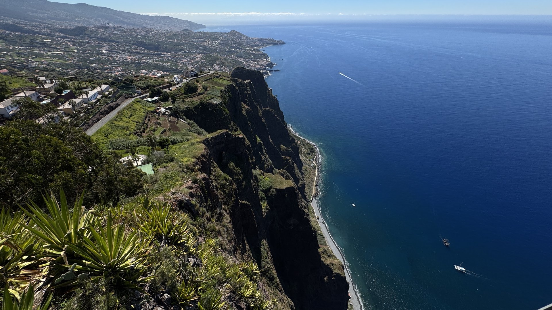 Pionowe klify Cabo Girão opadające do granatowego oceanu, w tle wybrzeże Funchal