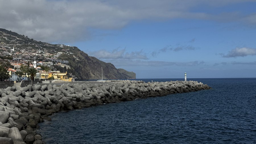 Falochron z latarnią w porcie Funchal i zabudowa miasta pod klifami