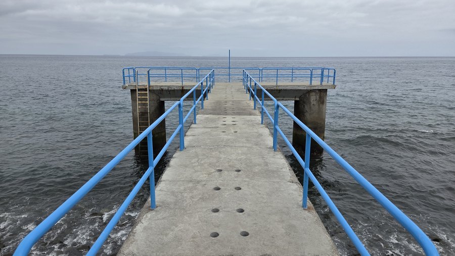 Betonowe molo z niebieskimi barierkami wchodzące w ocean w Santa Cruz