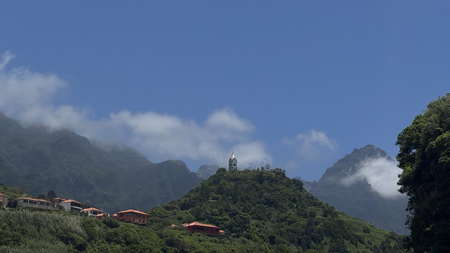 Kaplica na zielonym wzgórzu w São Vicente na tle gór w chmurach