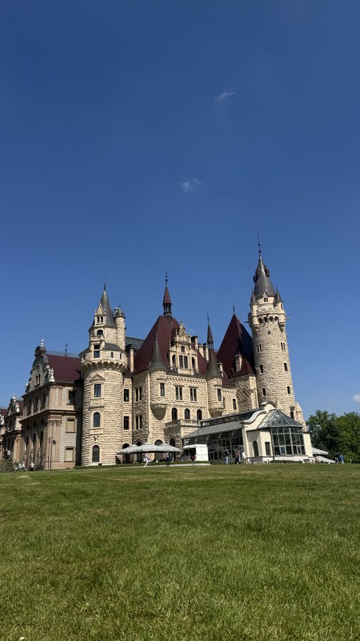 Bajkowa bryła zamku w Mosznej za rozległym trawnikiem parku
