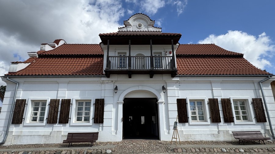 Biały ratusz z drewnianym balkonem przy brukowanym rynku miasteczka