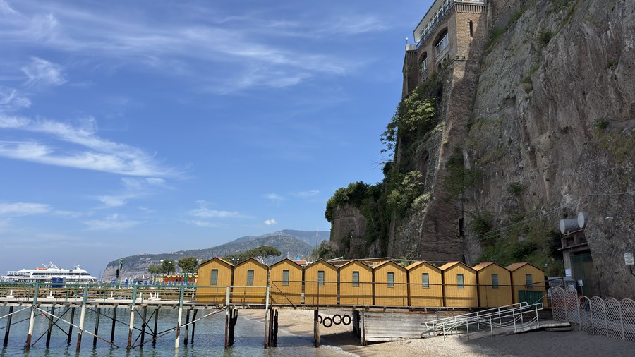 Żółte kabiny plażowe i pomost pod klifem w Sorrento
